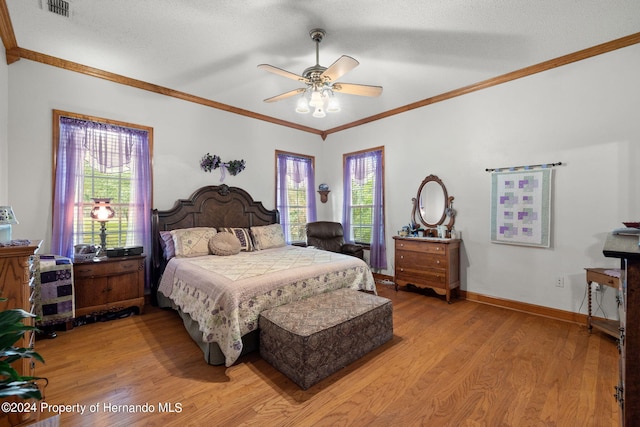 bedroom featuring ceiling fan, multiple windows, light hardwood / wood-style flooring, and a textured ceiling