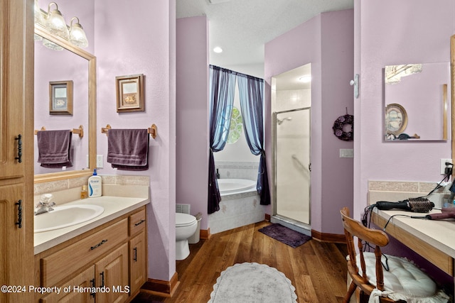 full bathroom featuring toilet, a textured ceiling, hardwood / wood-style flooring, vanity, and independent shower and bath