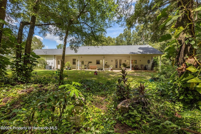 back of house featuring french doors and a lawn