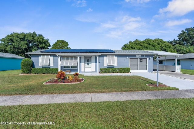 ranch-style home featuring a garage, a front lawn, and solar panels