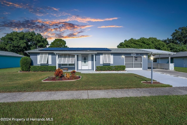 single story home with a lawn and solar panels