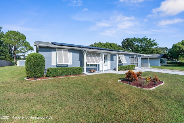 ranch-style house featuring solar panels and a front yard