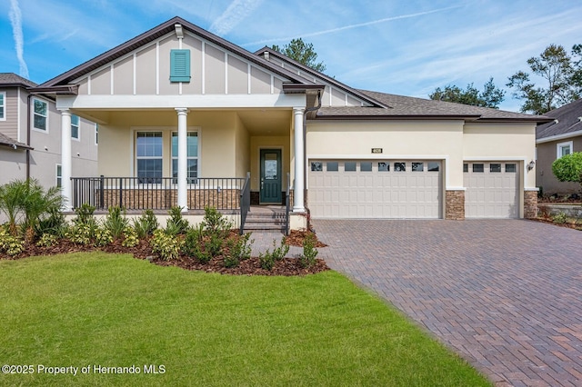 view of front of property featuring a garage, a front lawn, and a porch