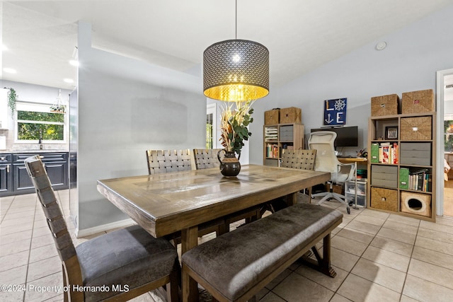 dining area featuring sink, light tile patterned floors, and vaulted ceiling