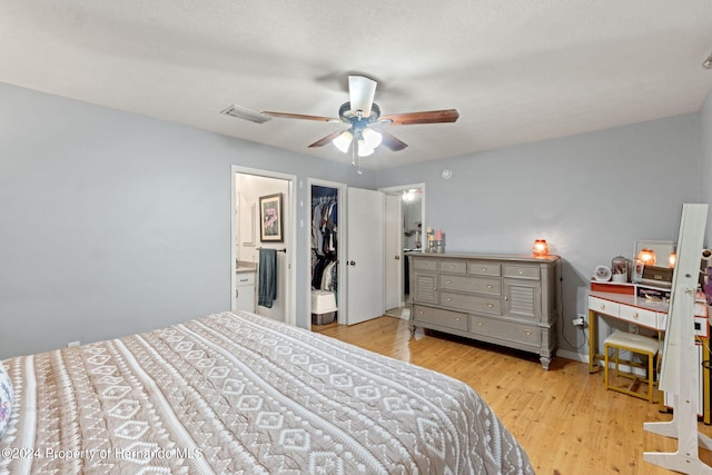 bedroom featuring connected bathroom, ceiling fan, a walk in closet, and light hardwood / wood-style floors