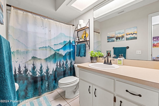 bathroom with tile patterned flooring, vanity, a skylight, and toilet