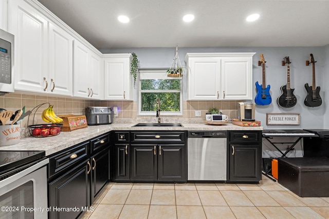 kitchen featuring sink, light tile patterned flooring, backsplash, white cabinetry, and appliances with stainless steel finishes