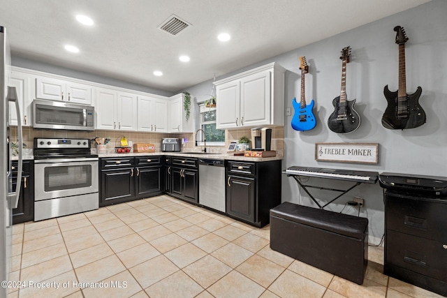 kitchen with light tile patterned floors, tasteful backsplash, sink, white cabinetry, and appliances with stainless steel finishes