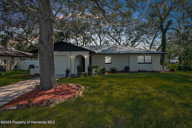 ranch-style home with a garage and a front lawn