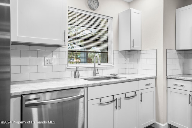 kitchen with white cabinetry, sink, light stone counters, appliances with stainless steel finishes, and tasteful backsplash