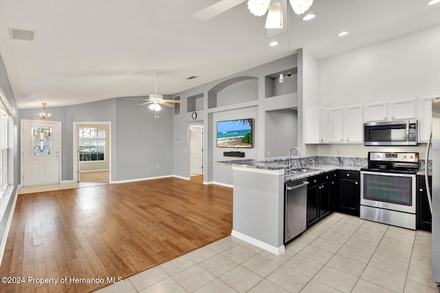 kitchen with white cabinetry, kitchen peninsula, appliances with stainless steel finishes, ceiling fan with notable chandelier, and light wood-type flooring