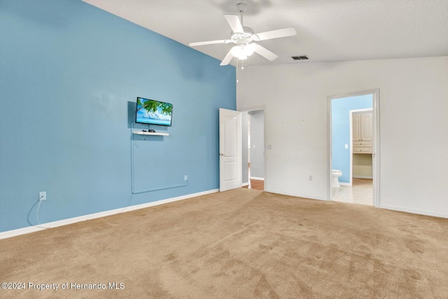 unfurnished bedroom featuring connected bathroom, ceiling fan, light colored carpet, and lofted ceiling