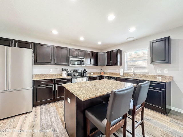 kitchen featuring a center island, a breakfast bar area, dark brown cabinets, light wood-type flooring, and appliances with stainless steel finishes