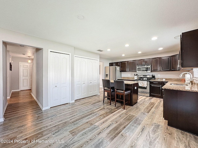 kitchen with a kitchen island, light wood-type flooring, appliances with stainless steel finishes, and sink