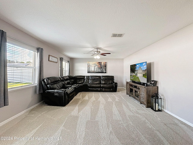 carpeted living room featuring ceiling fan and a textured ceiling