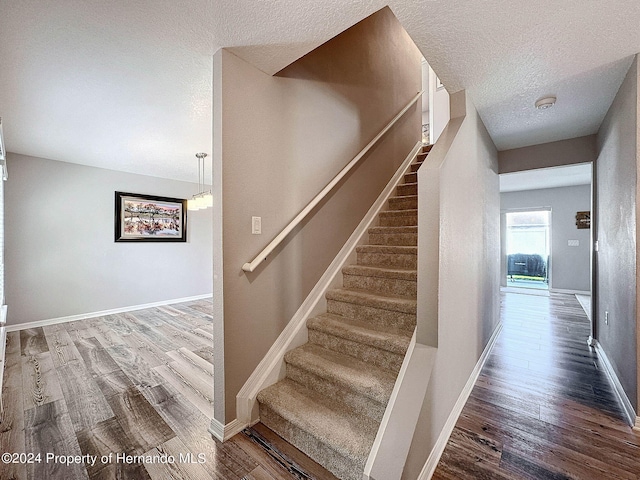 staircase featuring wood-type flooring and a textured ceiling