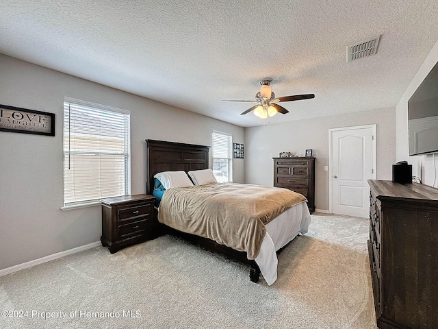 carpeted bedroom with multiple windows, a textured ceiling, and ceiling fan