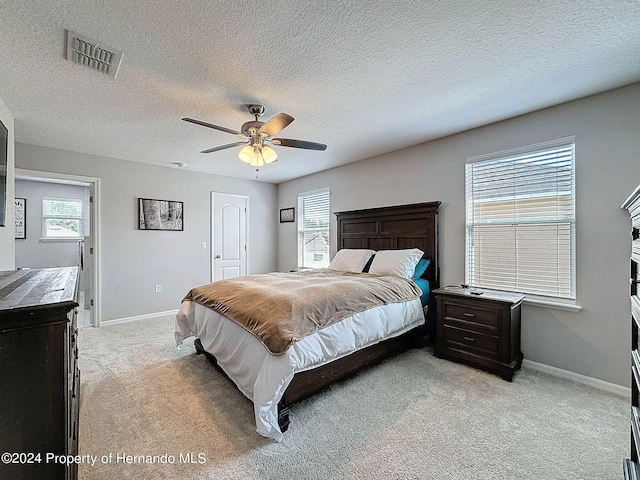 carpeted bedroom featuring ceiling fan and a textured ceiling