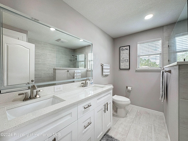 bathroom with tiled shower, a textured ceiling, toilet, and vanity