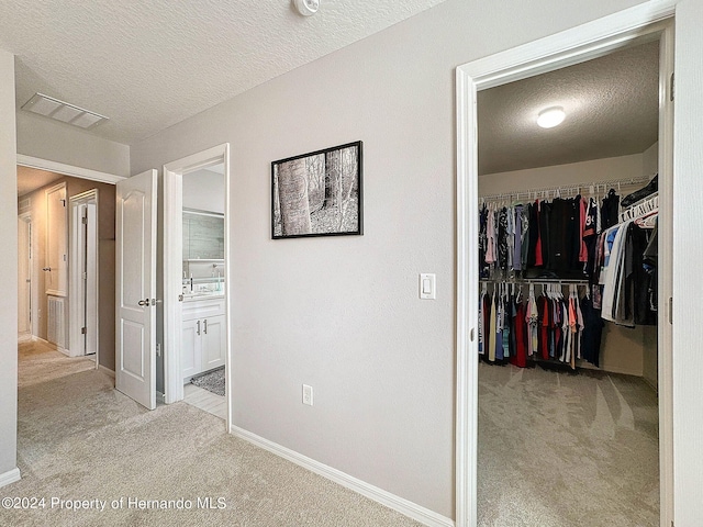 hall with light colored carpet and a textured ceiling