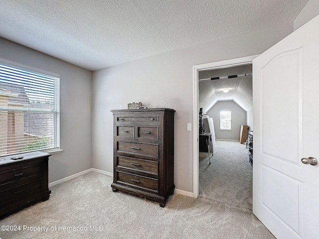 carpeted bedroom with a textured ceiling and vaulted ceiling