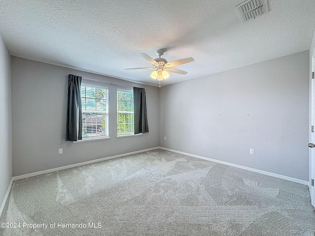 carpeted spare room with a textured ceiling and ceiling fan