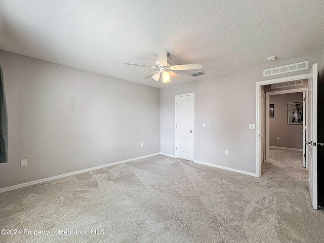 carpeted spare room featuring a textured ceiling and ceiling fan