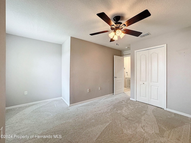 unfurnished bedroom featuring a closet, a textured ceiling, ceiling fan, and carpet floors