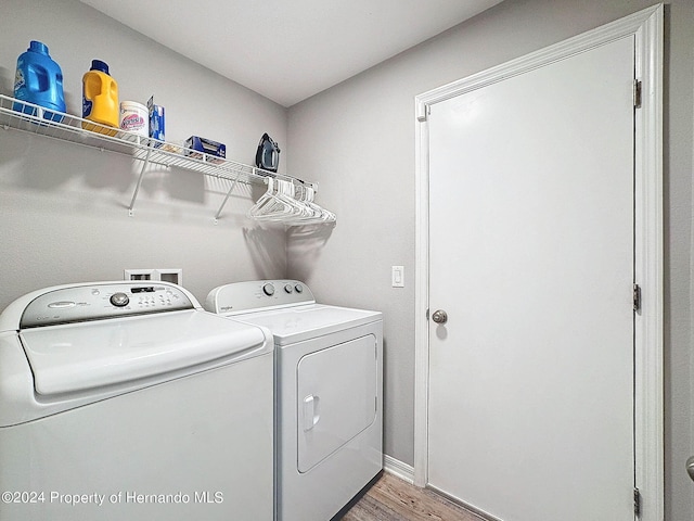 laundry room with washing machine and clothes dryer and light hardwood / wood-style flooring