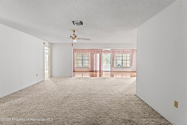 unfurnished room featuring a textured ceiling, ceiling fan, and carpet floors