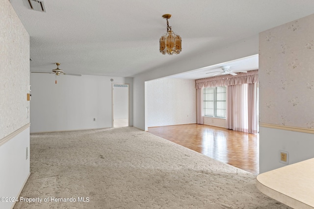 unfurnished living room with ceiling fan, a textured ceiling, and light parquet flooring