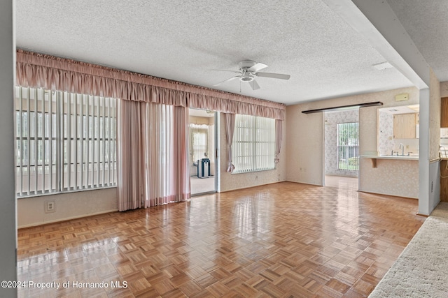 unfurnished room with a wealth of natural light, ceiling fan, and light parquet flooring