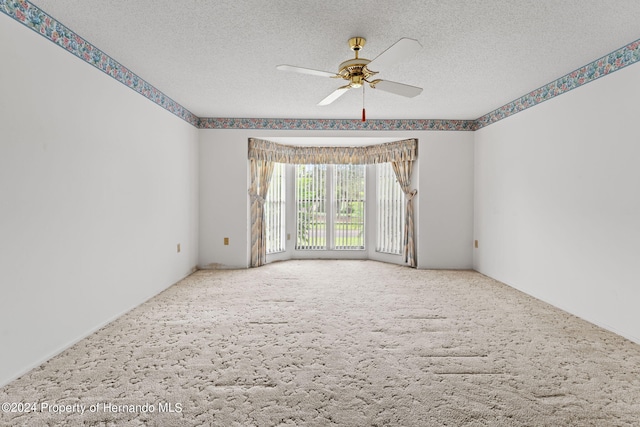 spare room with ceiling fan, a textured ceiling, and carpet flooring