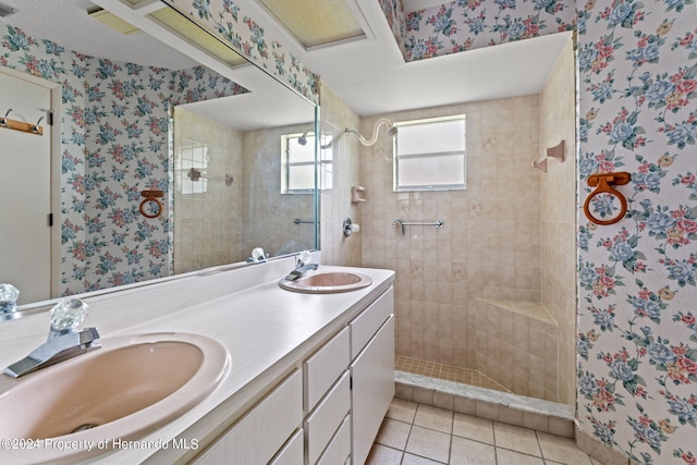 bathroom featuring tile patterned flooring, tiled shower, and vanity