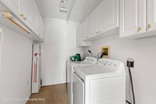 clothes washing area featuring washer and clothes dryer, cabinets, and a textured ceiling