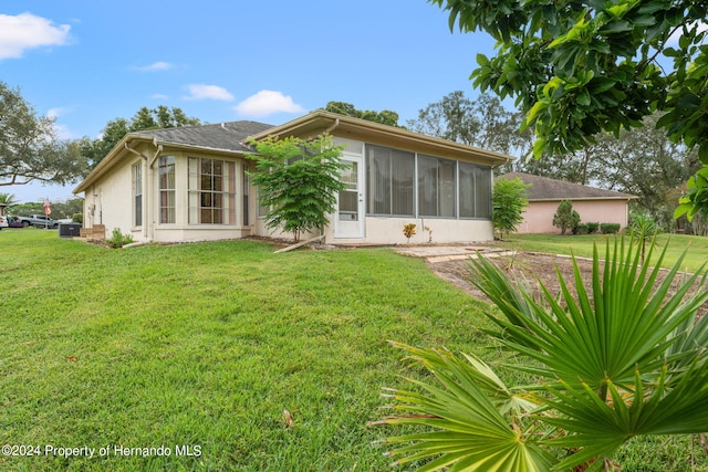 rear view of property with a lawn and a sunroom