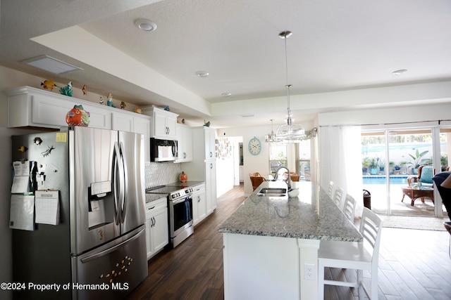 kitchen with sink, appliances with stainless steel finishes, decorative light fixtures, white cabinets, and dark wood-type flooring