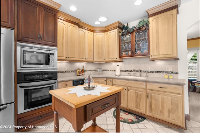 kitchen featuring decorative backsplash, appliances with stainless steel finishes, sink, and light tile patterned floors