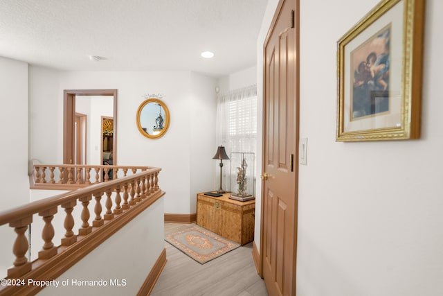 corridor with light hardwood / wood-style flooring and a textured ceiling