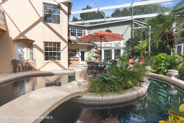 view of swimming pool featuring glass enclosure and a patio