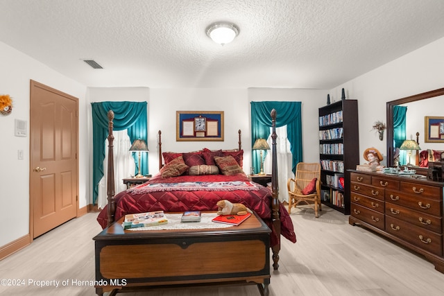 bedroom featuring a textured ceiling and light hardwood / wood-style flooring