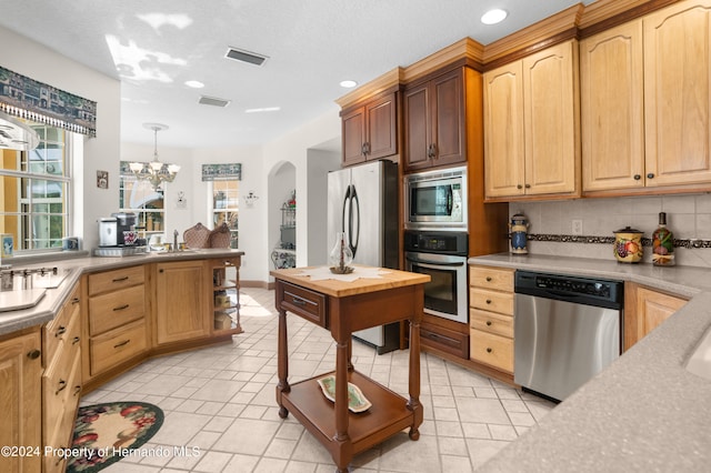 kitchen featuring stainless steel appliances, sink, tasteful backsplash, an inviting chandelier, and hanging light fixtures