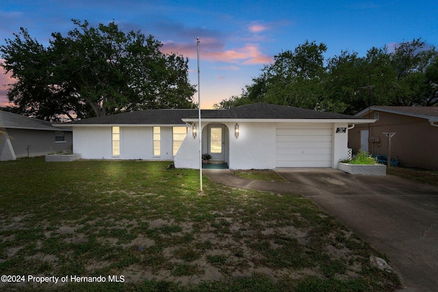 single story home featuring a garage and a lawn