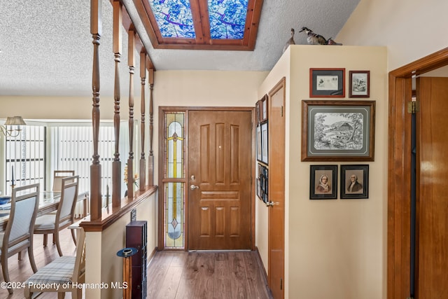 entrance foyer featuring vaulted ceiling, a textured ceiling, and dark hardwood / wood-style flooring