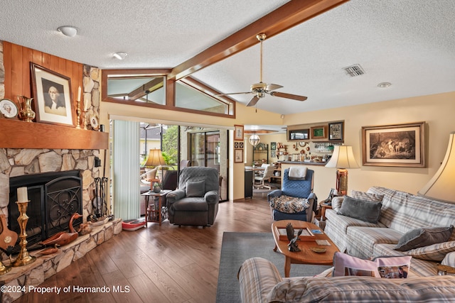 living room featuring dark wood-type flooring, a textured ceiling, a fireplace, ceiling fan, and lofted ceiling with beams