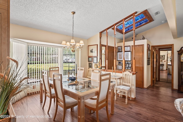 dining space featuring dark hardwood / wood-style floors, a textured ceiling, an inviting chandelier, and vaulted ceiling