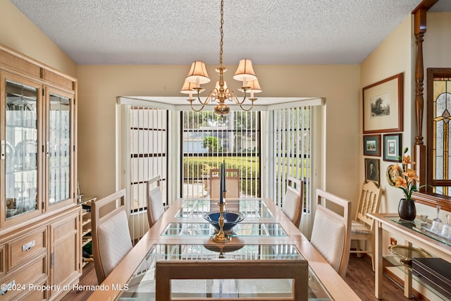 dining space featuring a textured ceiling, hardwood / wood-style floors, a healthy amount of sunlight, and an inviting chandelier