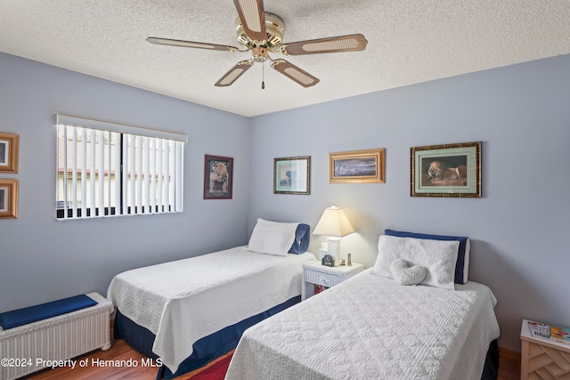 bedroom with hardwood / wood-style floors, ceiling fan, and a textured ceiling