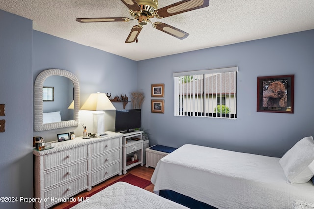 bedroom featuring dark hardwood / wood-style flooring, a textured ceiling, and ceiling fan