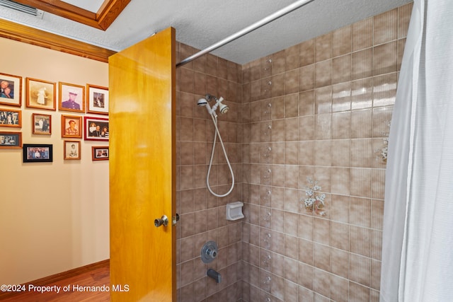 bathroom with hardwood / wood-style floors, shower / tub combo with curtain, and a textured ceiling